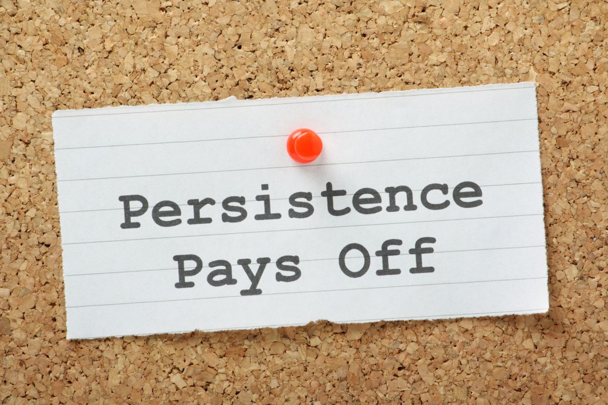 The photo shows a piece of paper with notes and a pin which means stay persistent until you get the job, the people who get their dream jobs are the ones who don't quit.