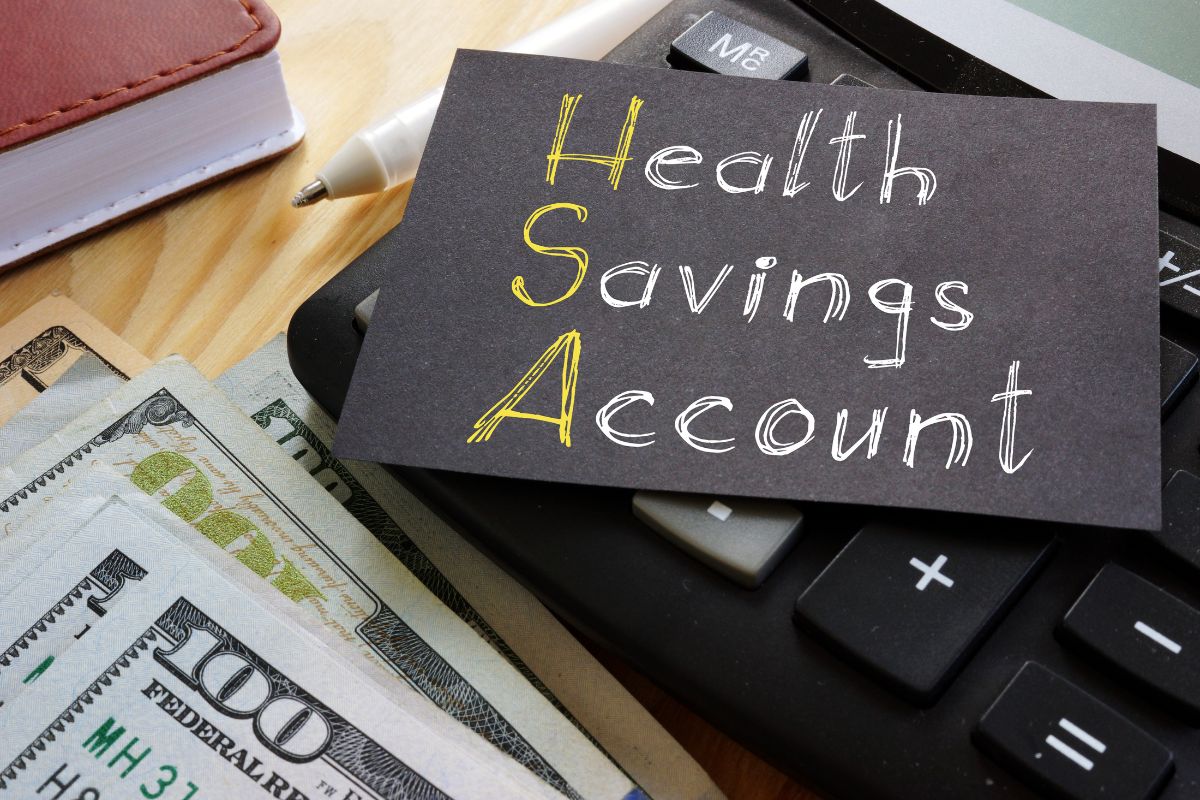The picture of a calculator, dollar bills, a notebook, and a piece of black paper with notes referring to taking advantage of health savings accounts is a smart way to handle medical expenses while lowering taxes.