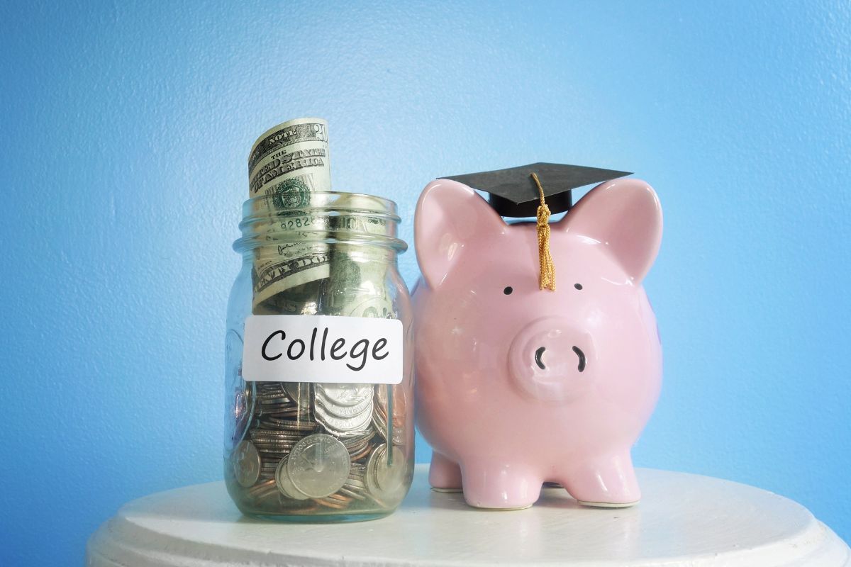 The photo shows a jar filled with coins and dollar bills with a note and a piggy bank with a graduate cap referring to the use of the lifetime learning credit to help cover tuition and education expenses.