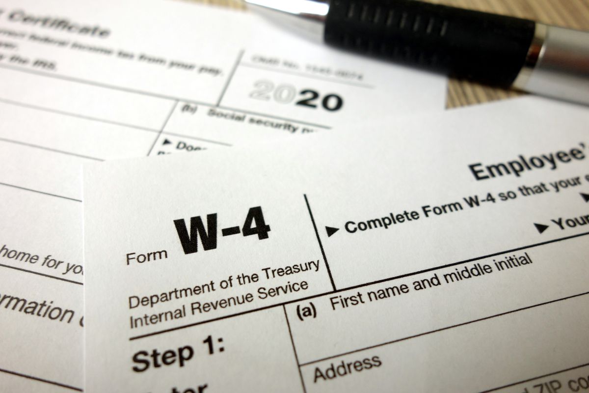 The image tells about a pen and paper with a note referring to adjusting your W-4 withholding ensures more take-home pay throughout the year.