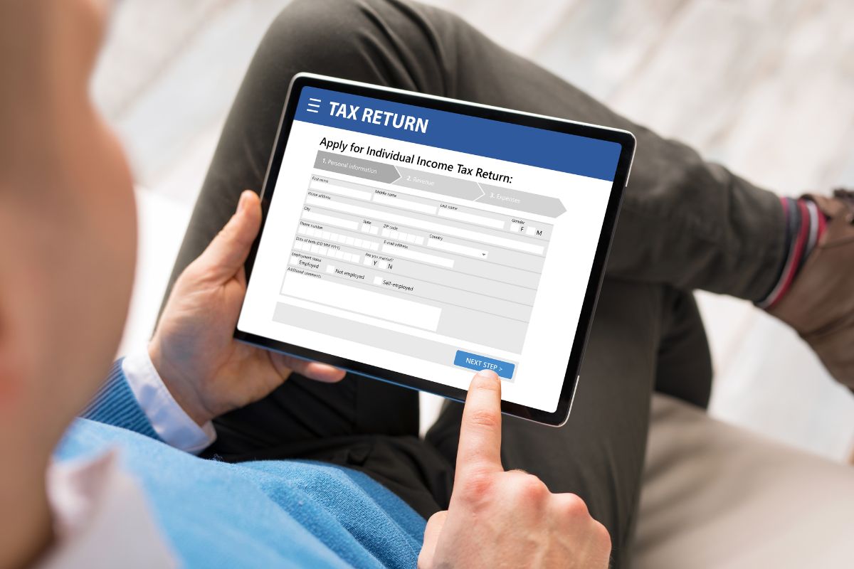 The photo shows a man using a tablet device which means filing your taxes online makes the process smoother and more efficient.