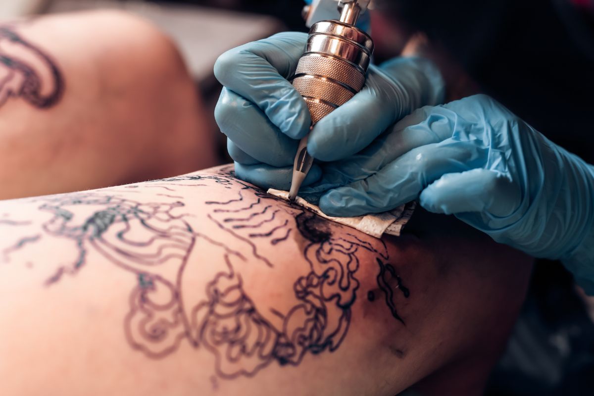 The picture shows an artist and a client indicating that paying in cash for a tattoo helps you avoid paying interest on something personal.