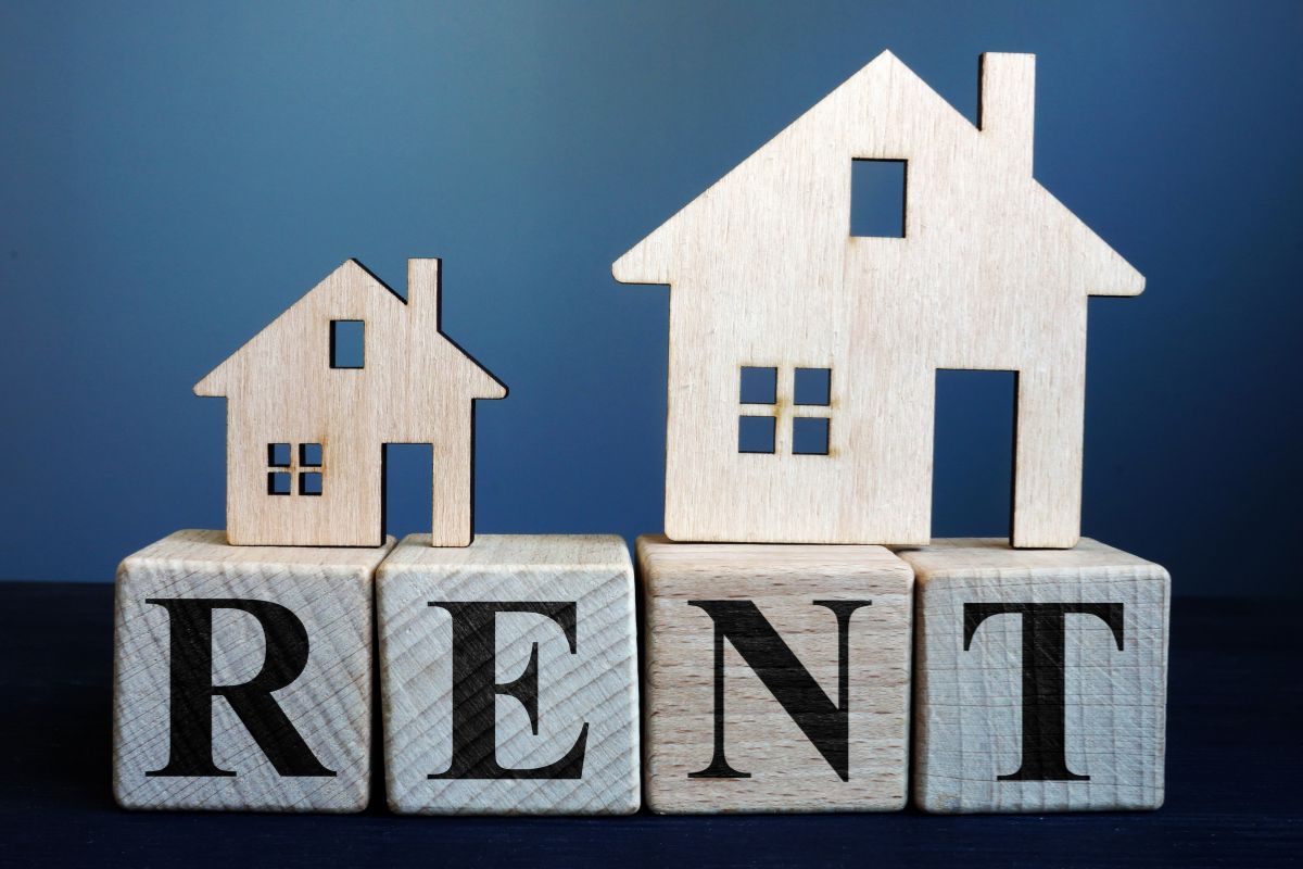 The photo shows wooden house figures and wooden cubes with letters referring to paying rent in cash can help you avoid those extra costs.