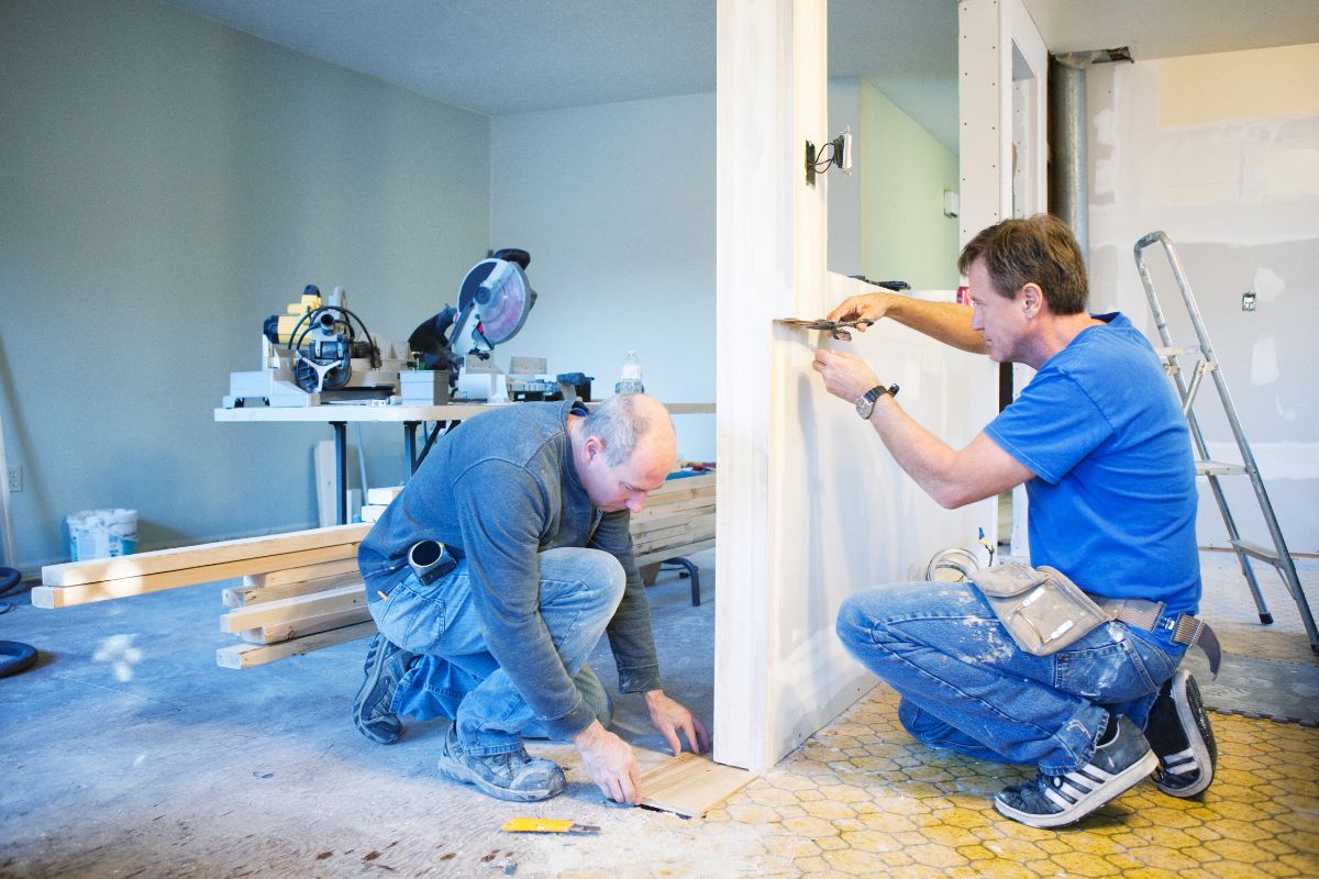 The picture tells about the materials and two men working on fixing the wall which means paying for the home renovations with cash ensures you don't end up with half-finished work and an empty wallet.