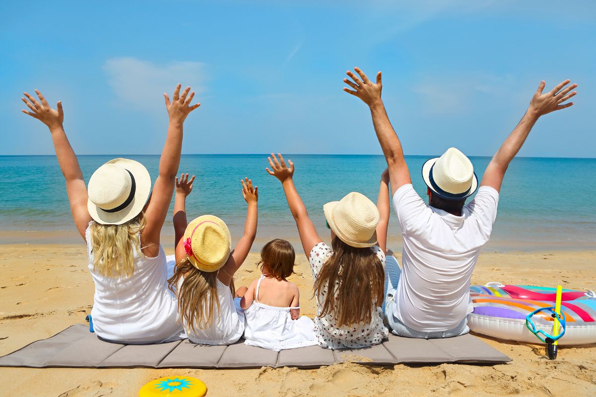 The image tells about a group of family enjoying the beach together referring to paying in cash for vacations helps keep travel expenses in check.