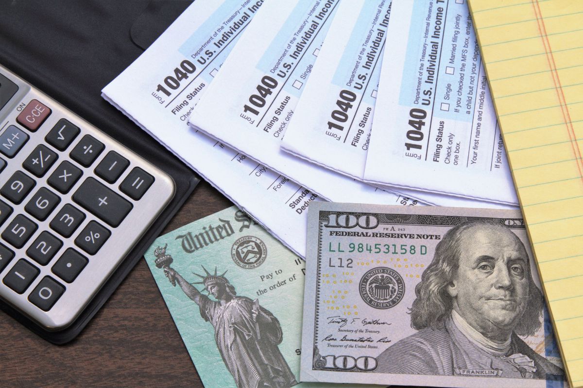 The picture shows a calculator, papers with notes, and a dollar bill referring to paying taxes in cash also helps avoid processing fees tied to credit transactions.