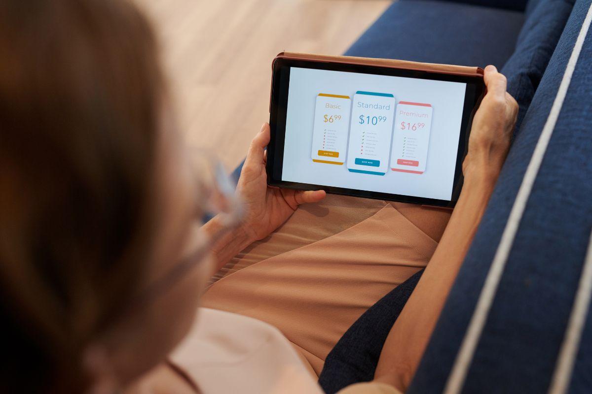 The picture tells about a girl holding a tablet device which means that canceling three subscriptions you don't need is an easy way to free up cash without extra work.
