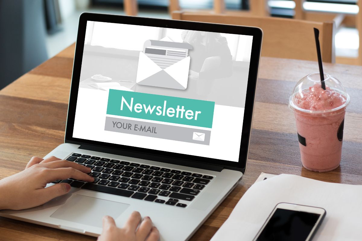 The picture shows a woman writing a newsletter on a laptop.