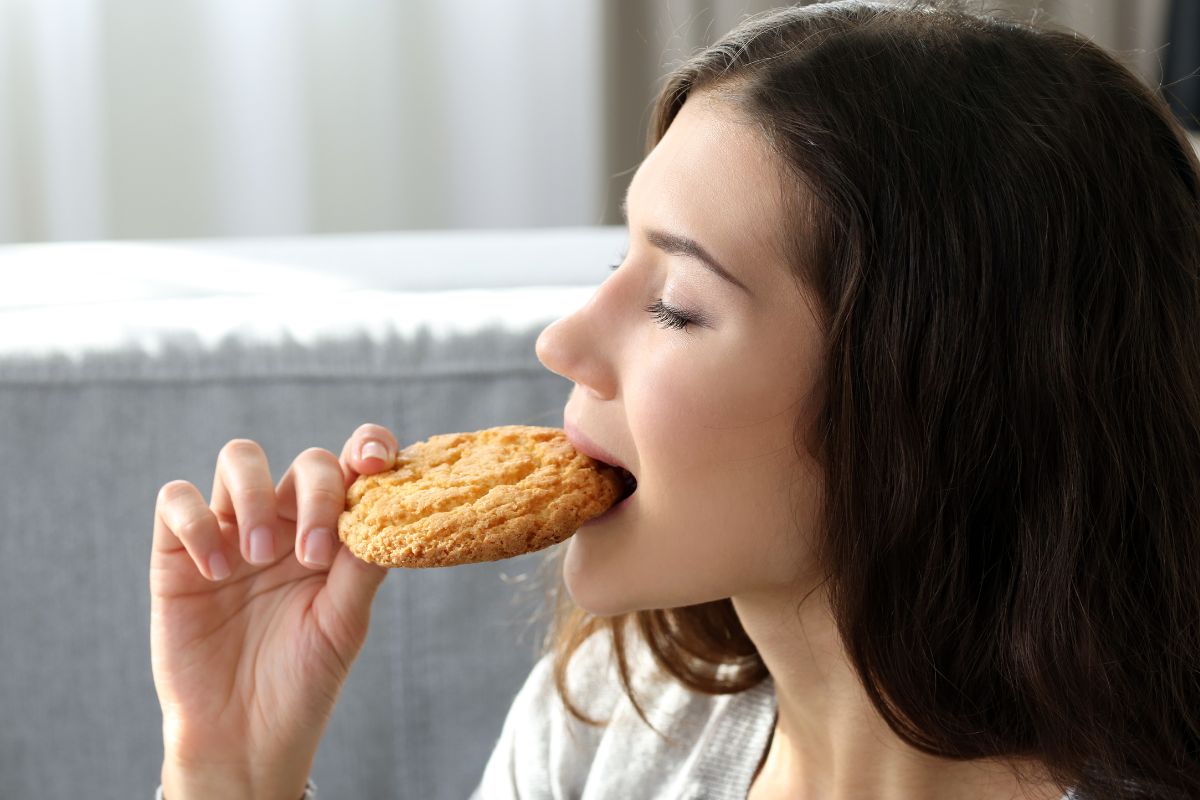 Photo shows a woman eating a cookie.