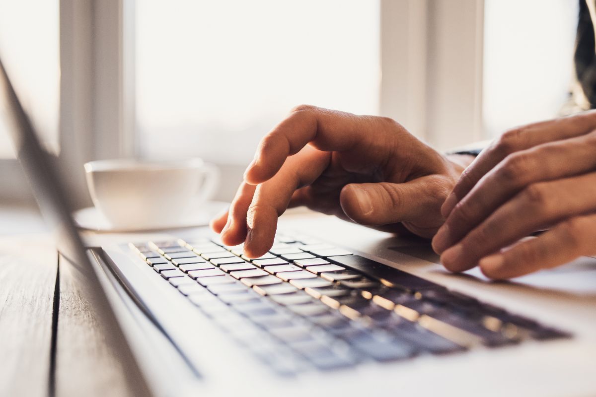 The photo of a man's hand using a laptop.