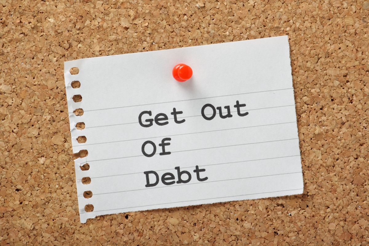 The picture shows a piece of paper with a pin and notes which means getting out of debt today and staying consistent can take control of your money and pay off debt faster.
