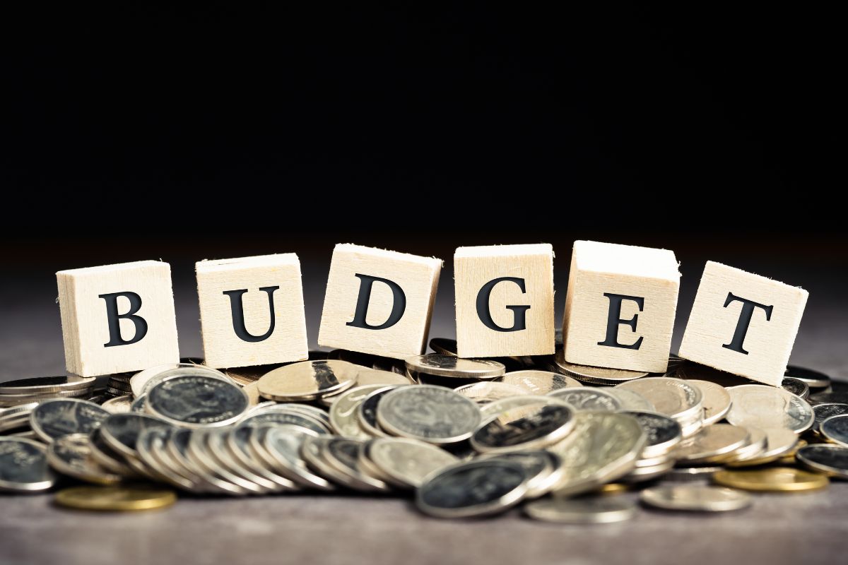 The photo shows coins and wooden cubes with letters indicating to try a fun budget with a limit that makes you more mindful without taking away all enjoyment.