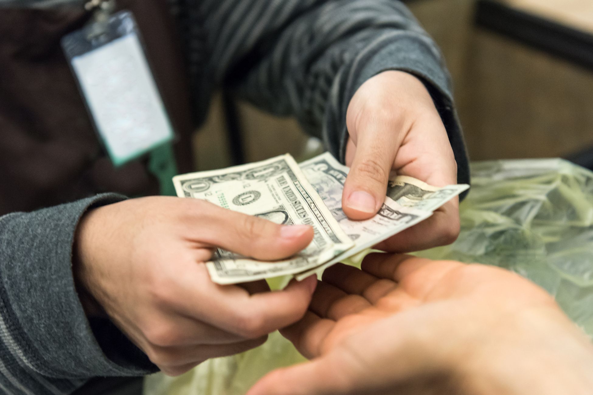 The image shows a woman's hand paying in cash.