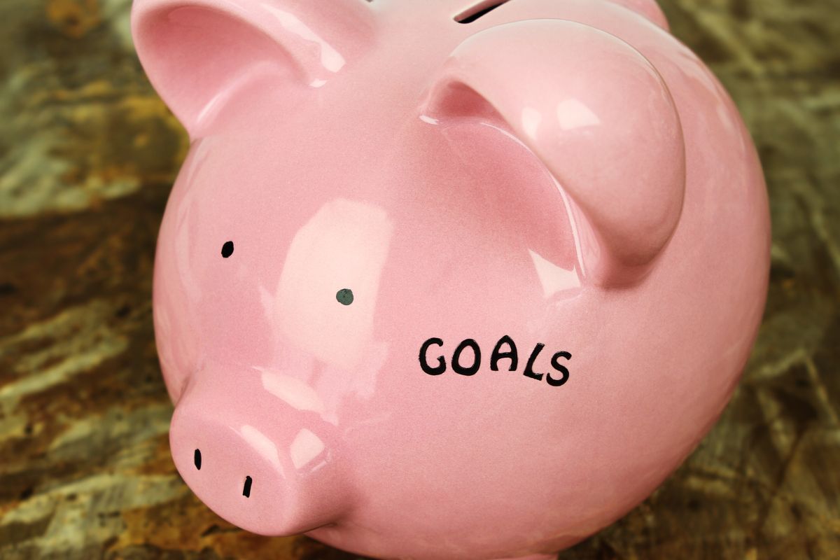 The image tells about a piggy bank with a note which means that creating a savings goal for something exciting makes frugal living more rewarding.