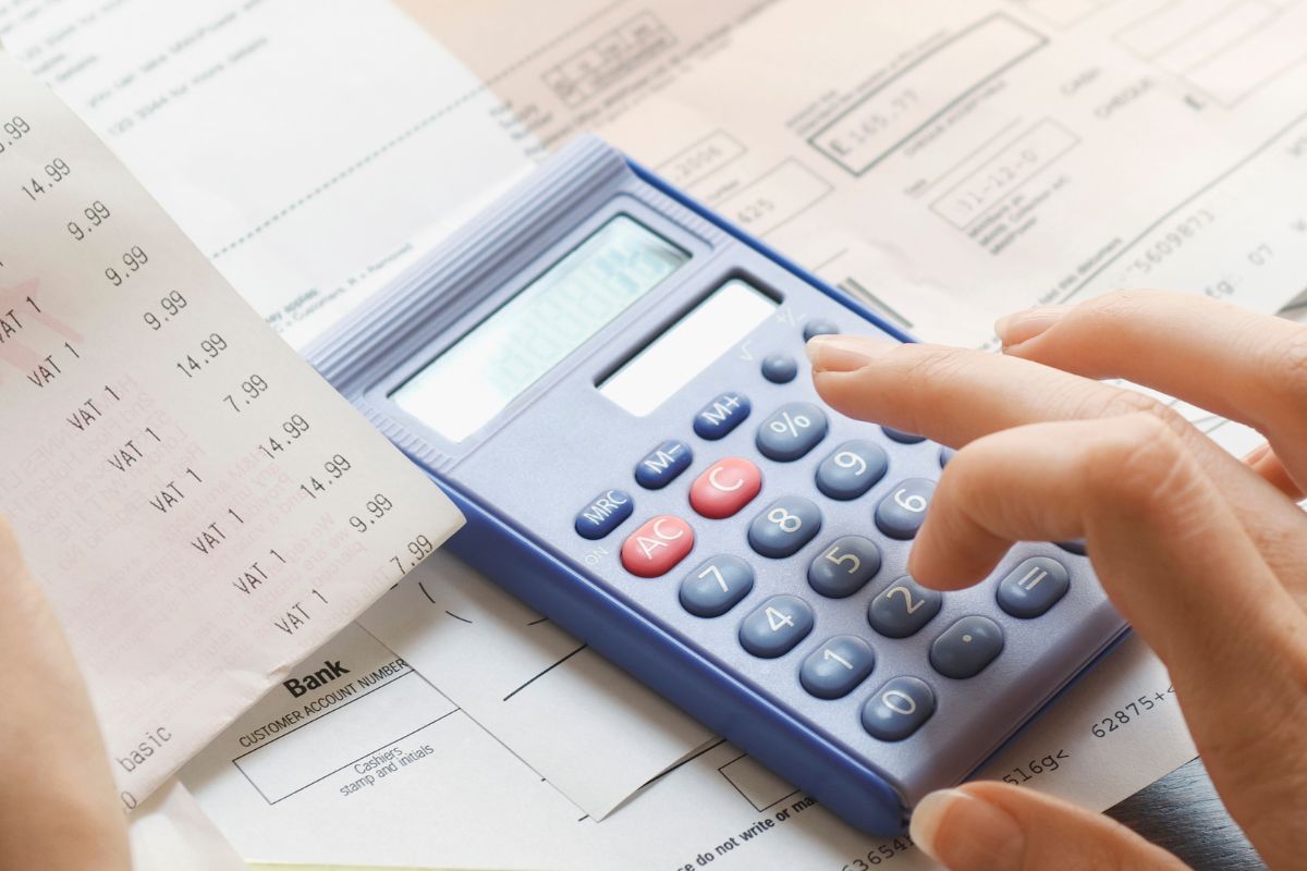 The image shows a woman's hand calculating expenses.