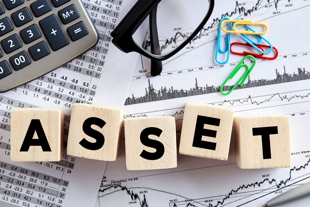 The image shows papers, a calculator, and an asset wording.