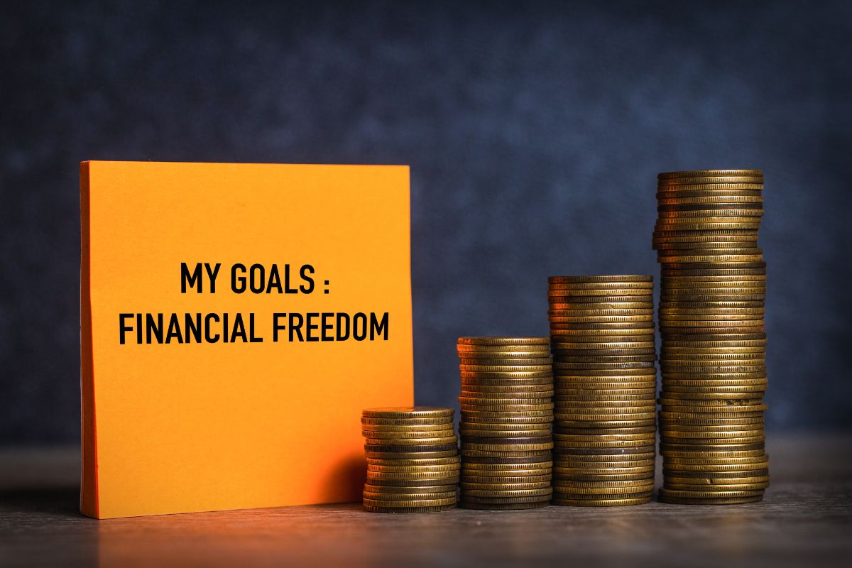 The picture shows coin stocks and a piece of paper with notes indicating to set freedom goals instead of retirement goal to avoid stress in the future.