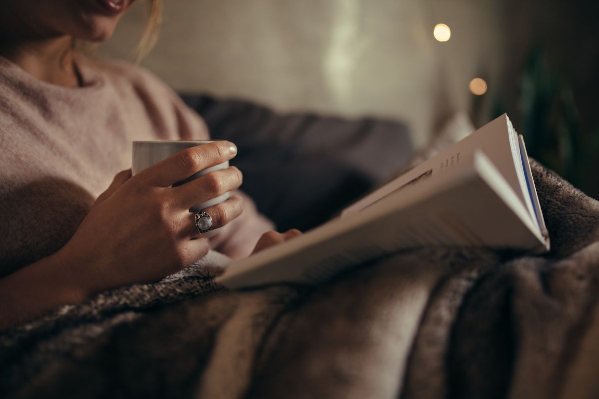 The picture of a girl reading a book while having a coffee which means investing in yourself by reading books helps build the mindset and strategies needed to create wealth.