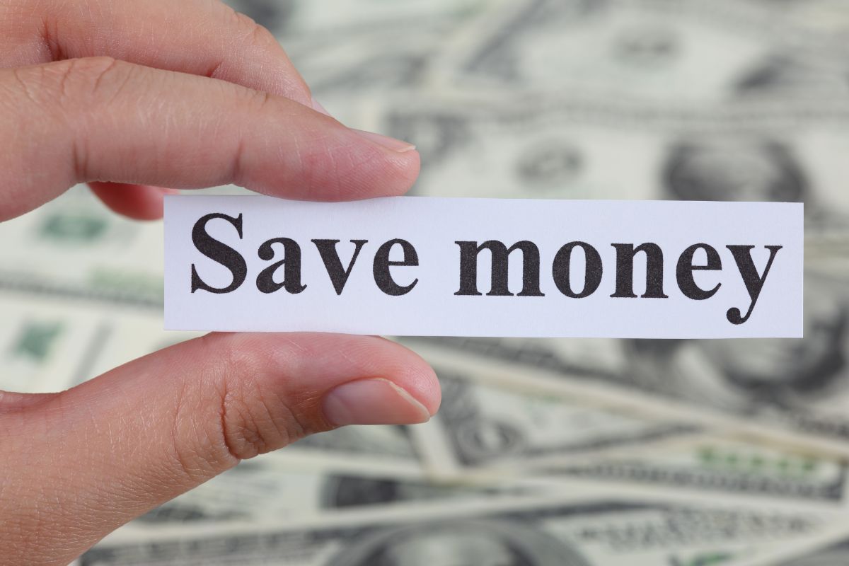 A woman's hand holding a paper with save money wording.
