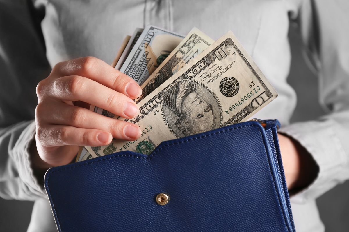 An image of a woman putting back her money in a wallet.