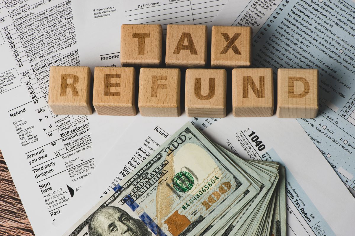 The image tells about papers, dollar bills, and wooden cubes with letters referring to the use of windfall for lump-sum debt payments helps you get ahead without needing to change your monthly budget.