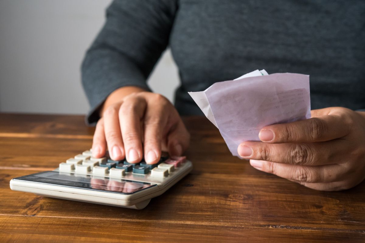 The image shows a girl's hand calculating the receipts on her hand which means tracking every expense in real-time keeps your budget accurate.