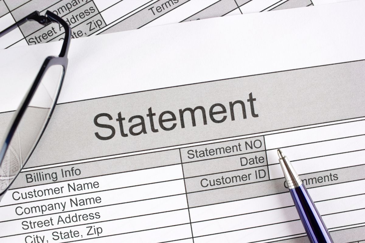 The image tells about an eyeglass, a pen, and papers with notes referring to reviewing bank and credit card statements regularly helps you catch errors and see if you're overspending.