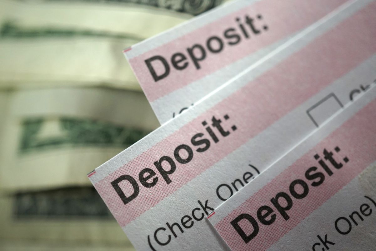 The image shows dollar bills and papers with notes which means to trick yourself into thinking you earn less makes it harder to spend and easier to build a habit of savings.