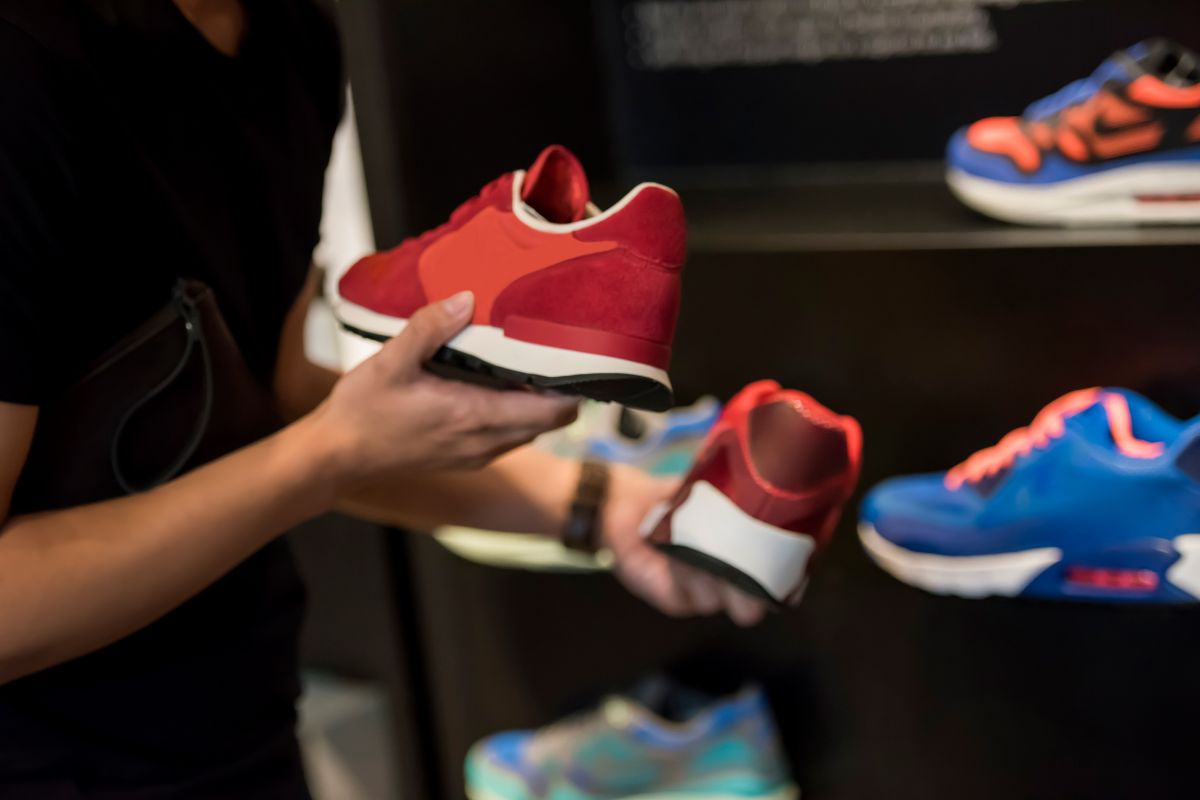 The picture shows a man's hand holding a pair of shoes at the store which means associate spending with effort makes you think twice about impulse purchases.