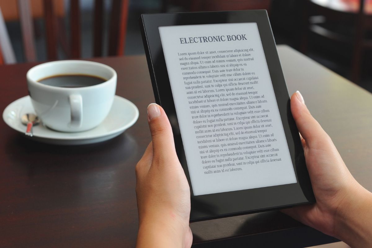 The photo shows a coffee and a girl's hand holding a tablet device with a screen display referring to creating and selling digital products as a beginner-friendly way to make money online.