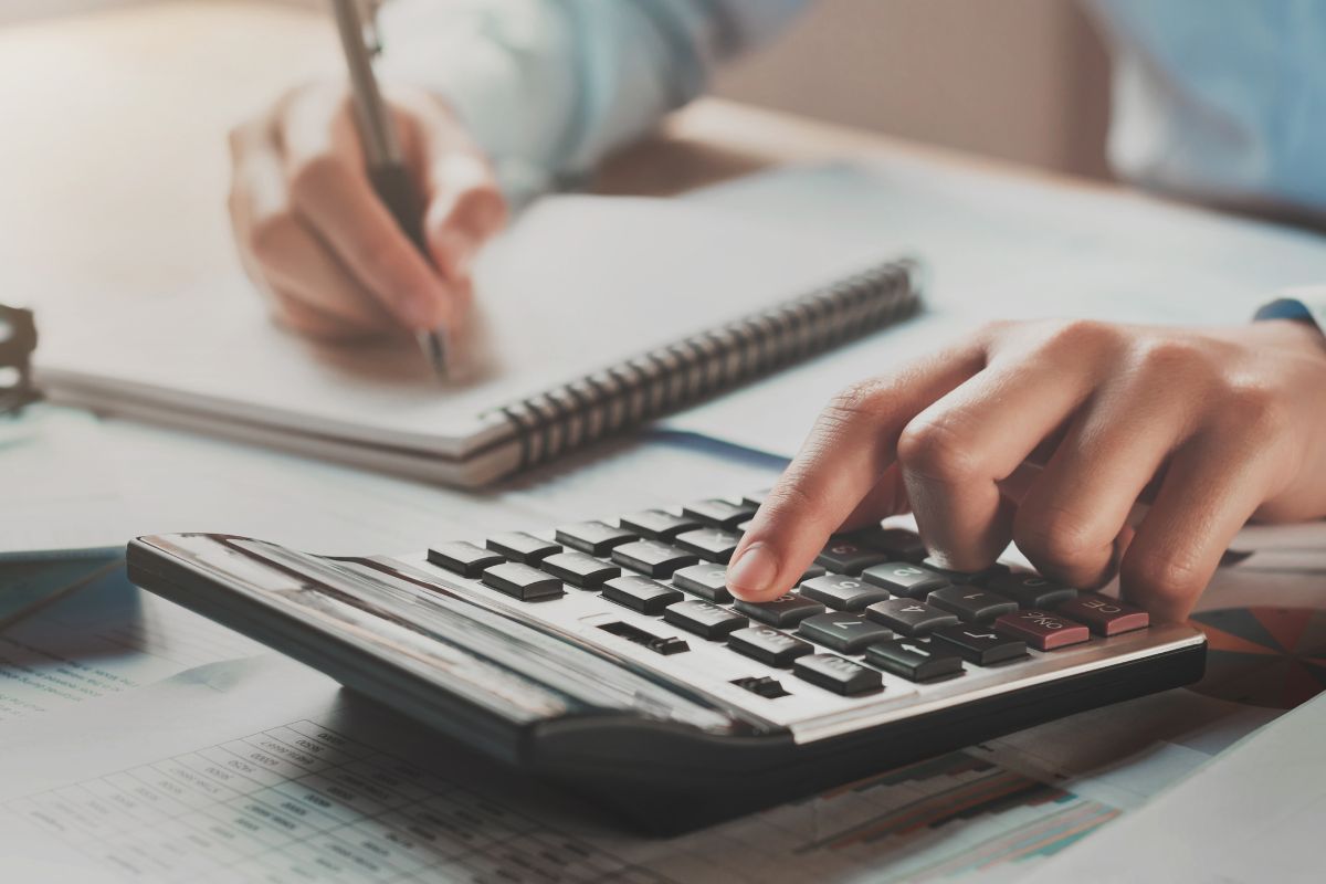 The image tells about a man's hand and writing in the notebook while calculating which means time to budget like a pro sticking to these steps helps you take control of your money and avoid financial stress.