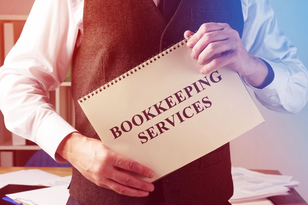 The picture of papers on the table and a man holding a notebook with notes which refers to doing bookkeeping for other businesses is a solid way to make money online.