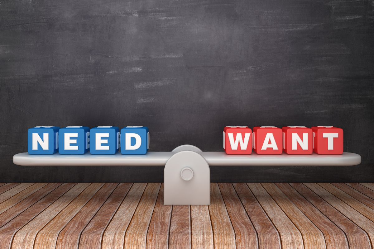 The picture shows a seesaw scale with cubes and letters which means that prioritizing needs over wants can help free up money for savings or paying off debt.