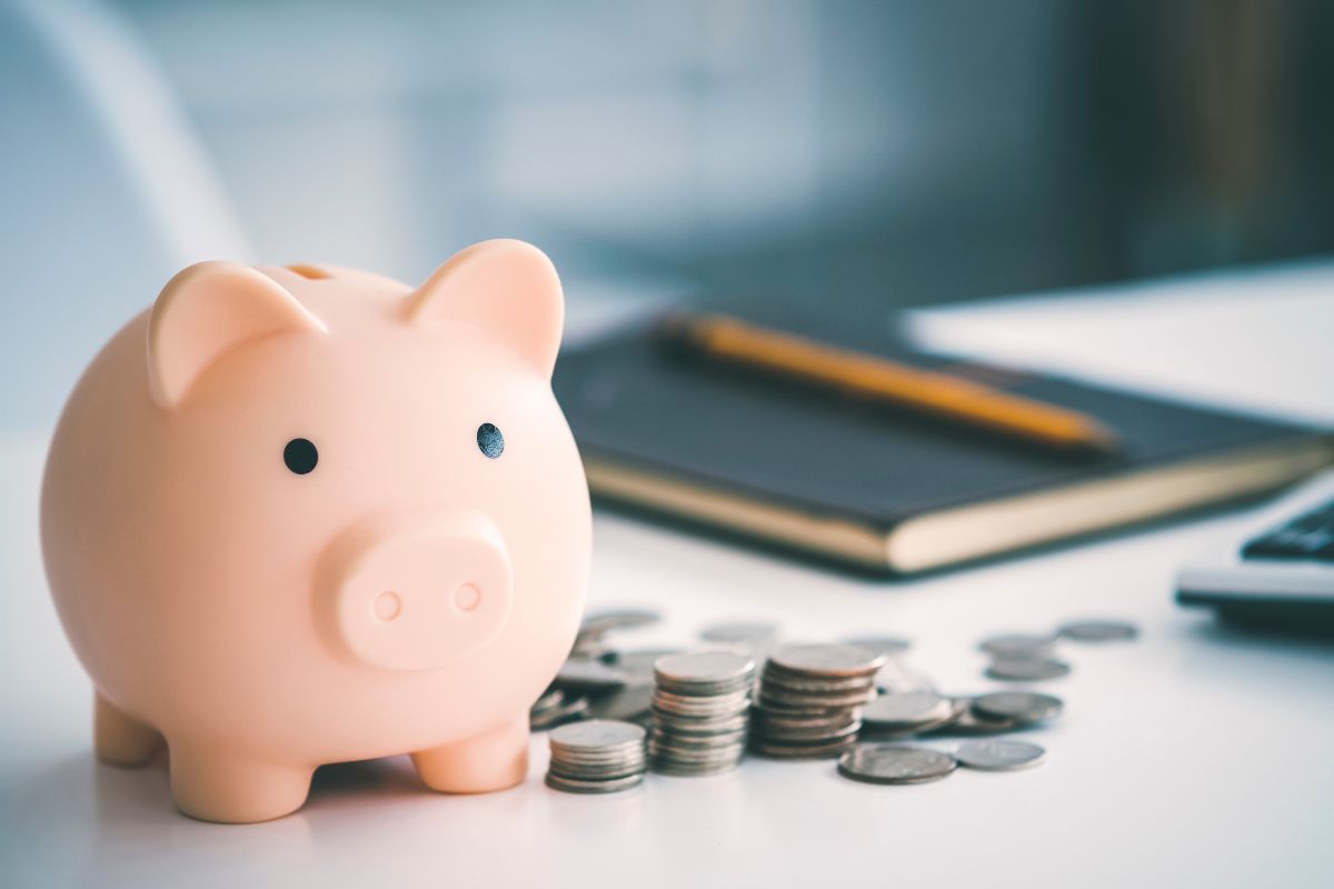 The image tells about a pen, a notebook, a calculator, coins, and a piggy bank which refers to automated savings and payments that help you stay on track without extra effort.