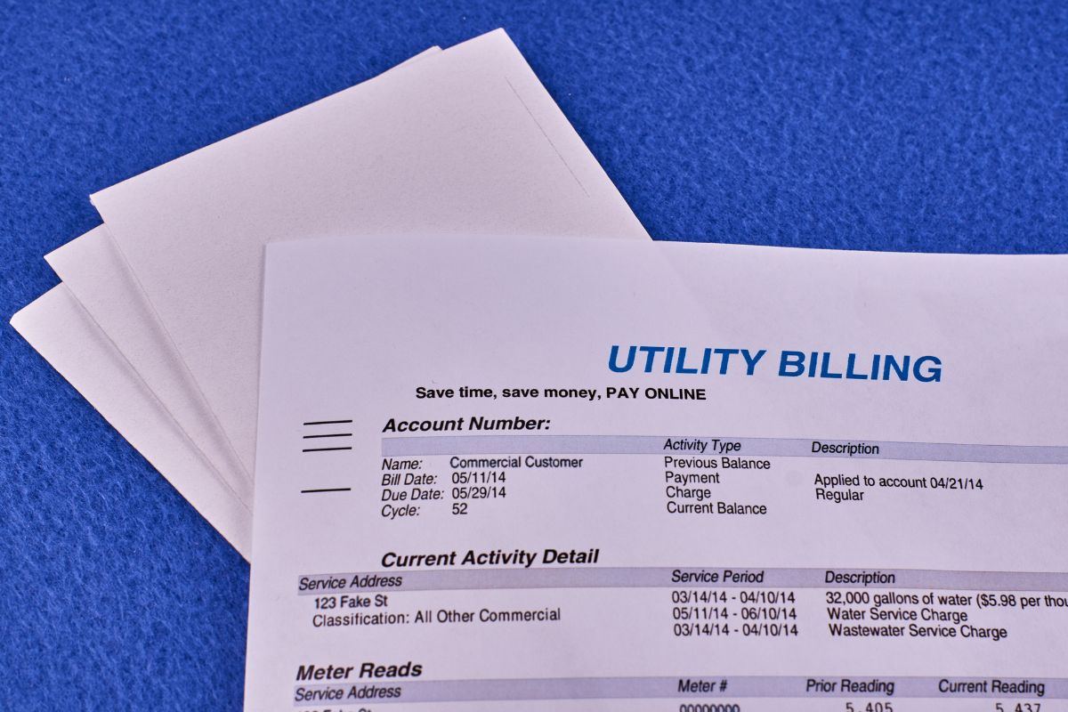 The picture shows envelopes and a piece of paper with notes indicating that utilities keep your home running and should always be factored into your budget.