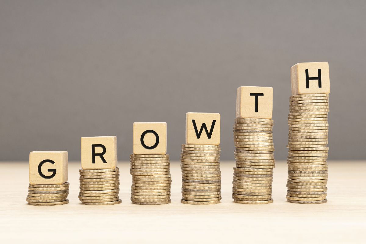 The image tells about coin stock and wooden cubes with letters referring to setting aside money allowing money to grow through compounding interest and letting money work for you means less stress about the future.