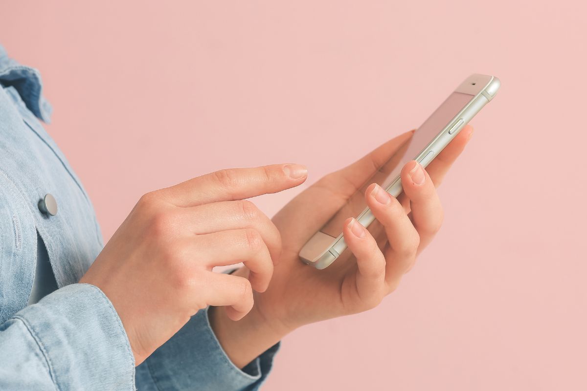 The picture tells about a girl's hand using a phone referring to using a savings app that rounds up purchases is an easy way to build savings without changing your budget.