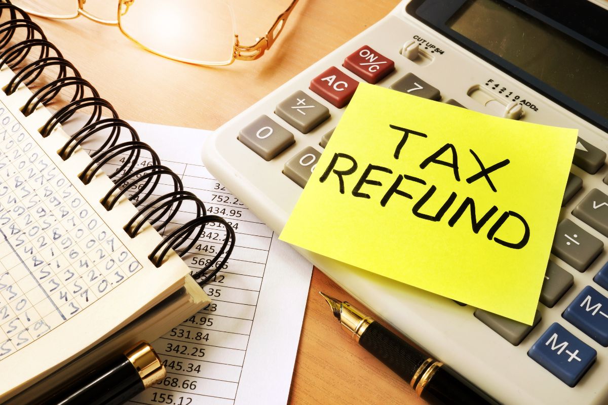 The image tells about a notebook, a pen, an eyeglass, a calculator, and a piece of paper with notes which means that converting unexpected income directly into savings is a great way to boost savings without affecting your budget.