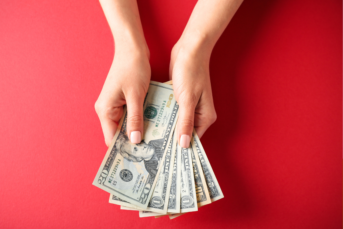 The picture shows a girl's hand holding dollar bills which means to pay yourself in cash and physically store savings that works well if you struggle with digital accounts accounts where money is easy to transfer. 
