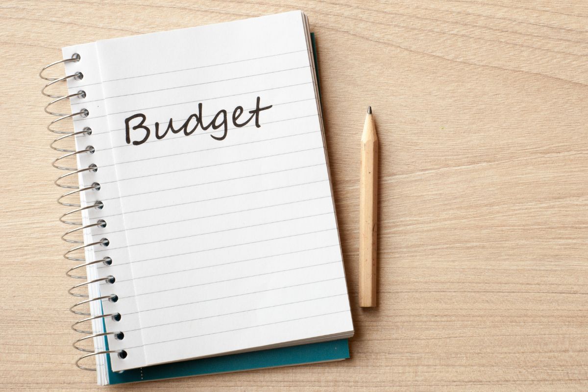 The picture tells about a pen and a notebook with a note which means creating a budget for essential expenses only helps you see where your money goes and what's truly important.