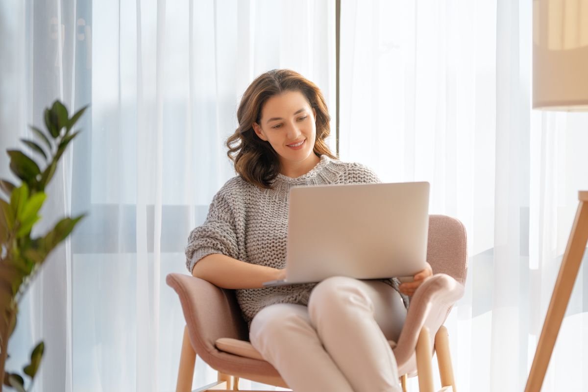 The photo shows a girl sitting on a chair while using a laptop which refers to the use of a visual tracker to stay motivated and easier to stay on track when the results are visible.