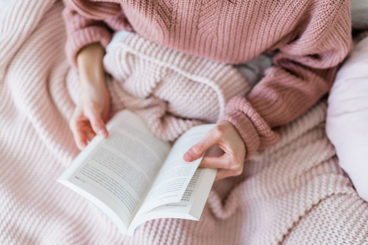 The picture shows a girl reading a book referring to plan-free activities to avoid boredom spending and reduce the urge to shop out of habit.