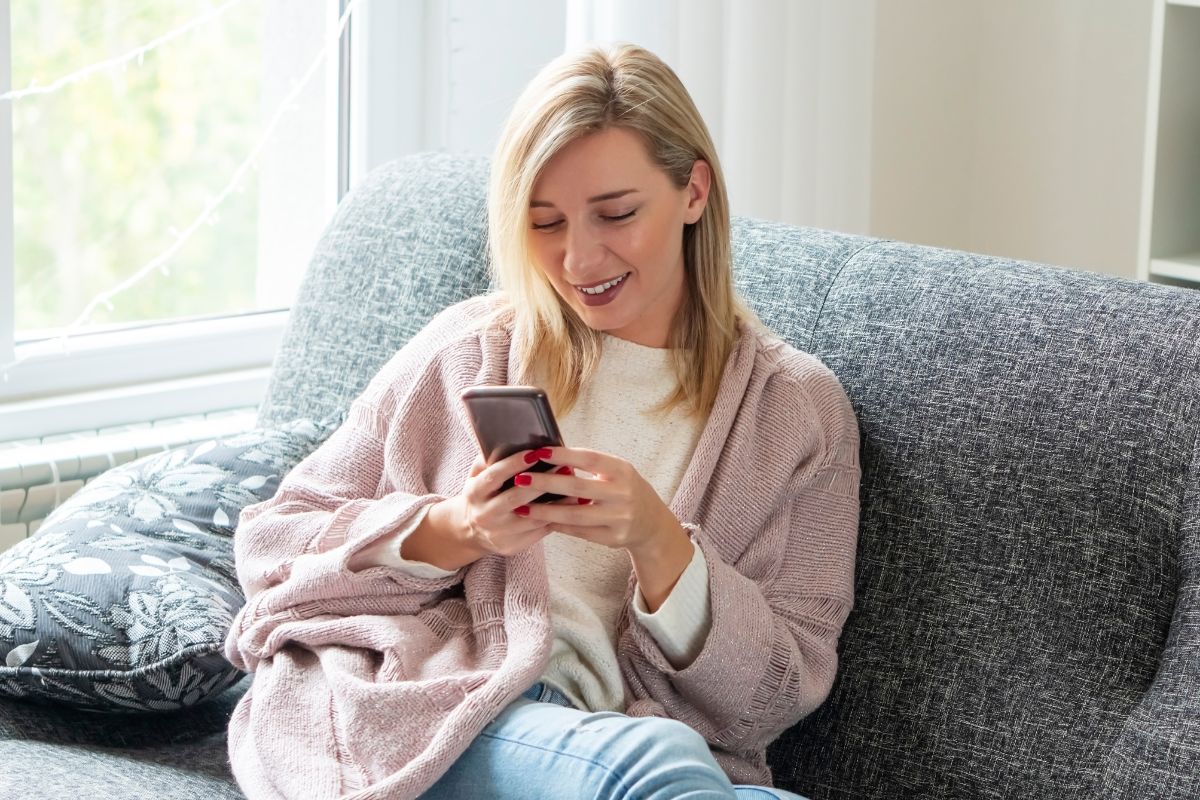 The picture tells about a girl sitting on the couch while using a phone which means unsubscribing from store emails helps avoid impulse spending and makes it easier to stick to the challenge.