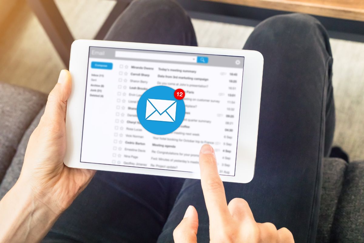 The image shows a man's hand using a tablet device with a screen display indicating to unsubscribe from marketing emails making it easier to resist spending.