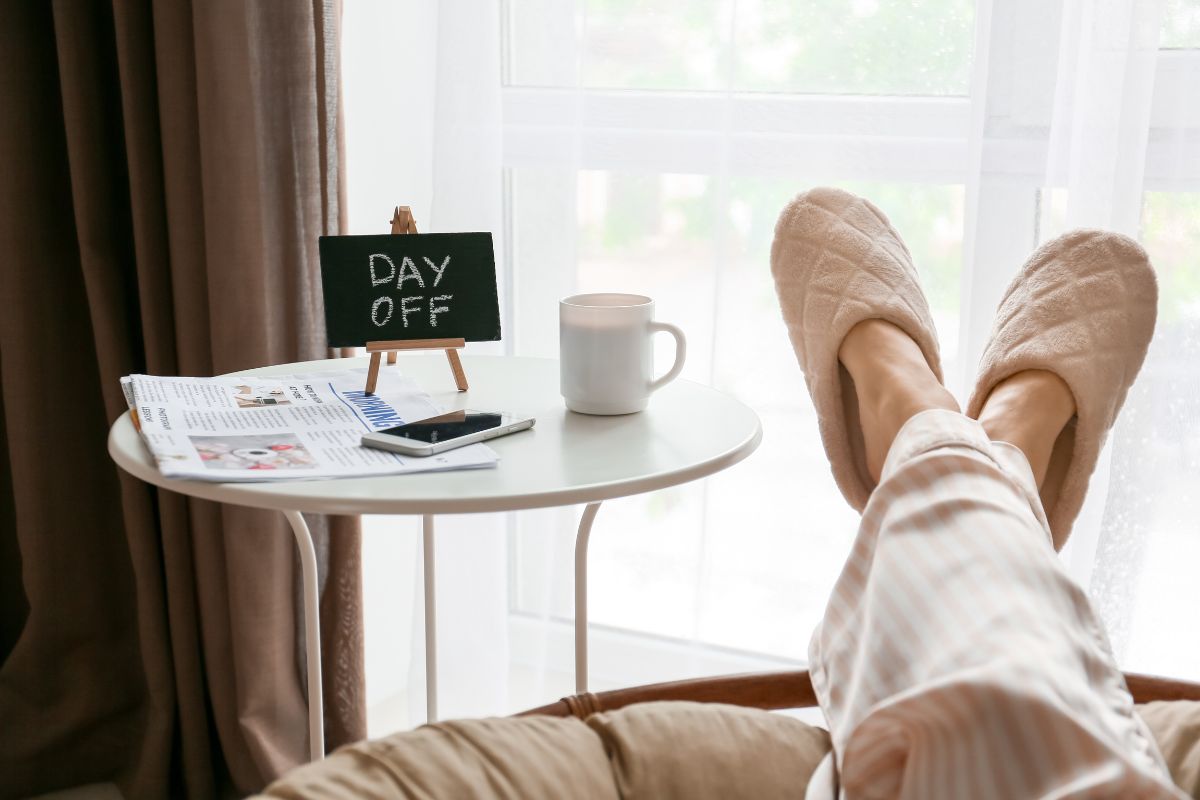 The image shows a coffee, a magazine, a phone, a board with notes, and a girl's feet relaxing referring to to setting a reward for competing for the challenge to look forward to keeps motivation high.