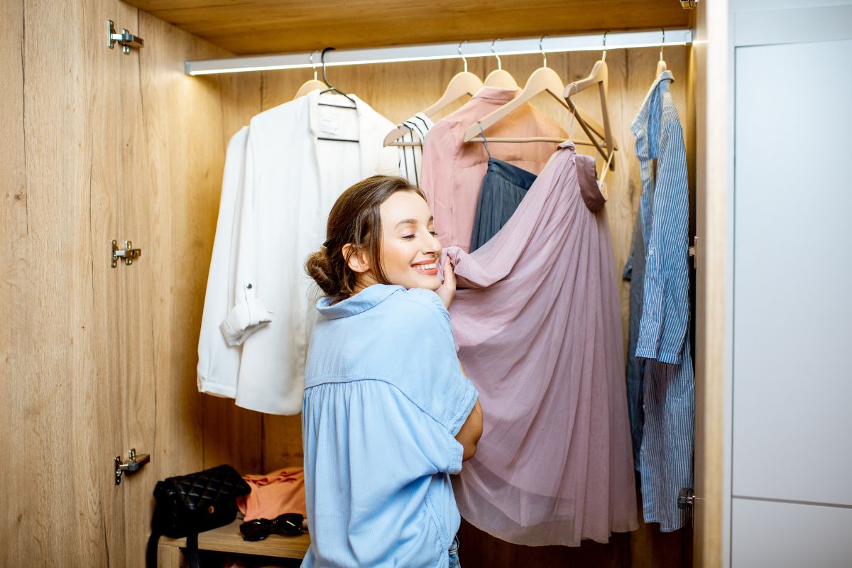 The image shows clothes in the wardrobe and a girl picking up one referring to wearing only a set number of outfits helps build appreciation for what's already owned.
