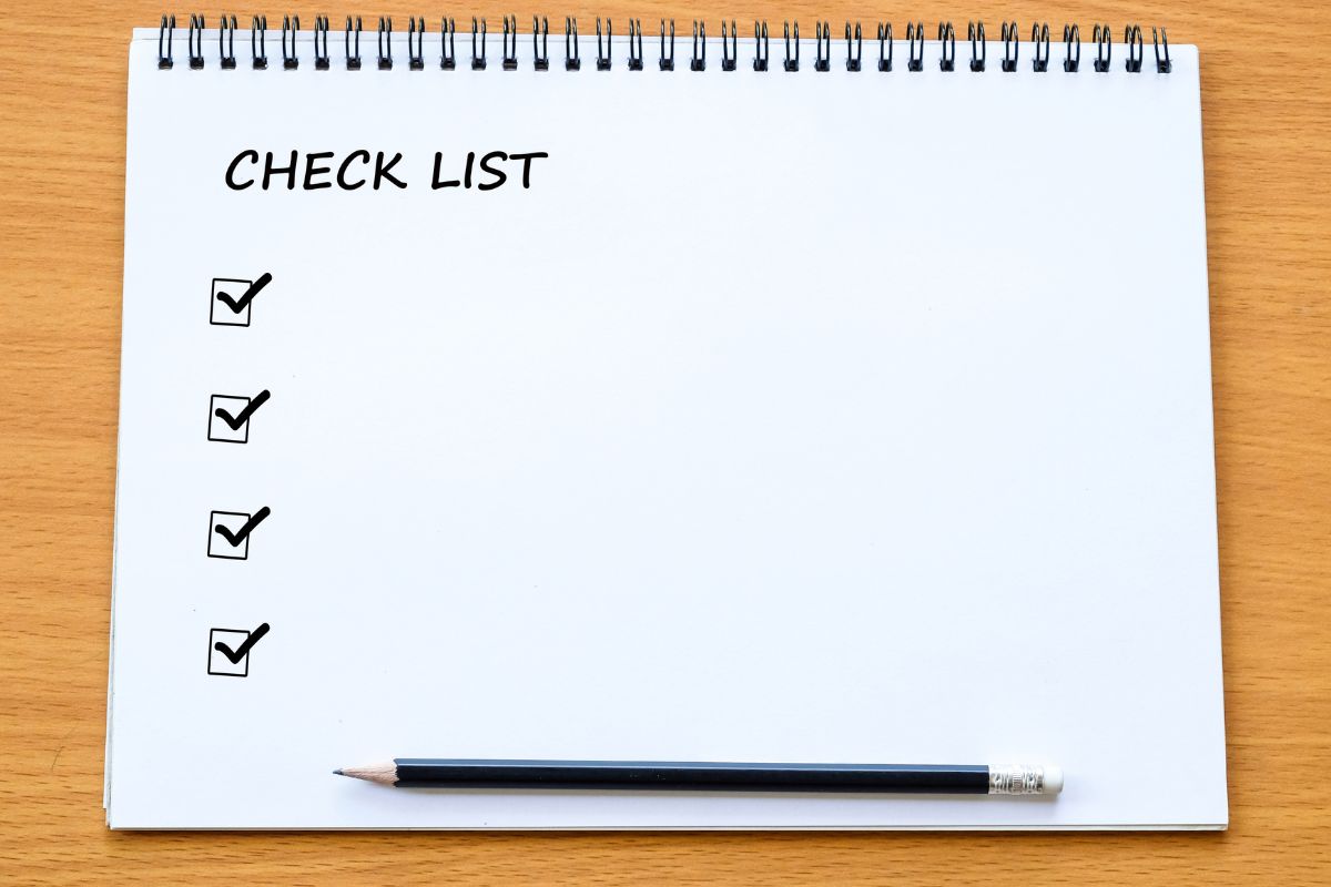 The image tells about a pen and a notebook with notes referring to the use of a needs vs. wants checklist to help you stick to your budget while avoiding unnecessary spending.