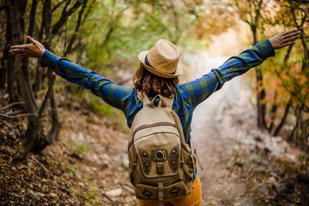 The photo tells about a girl carrying a backpack while enjoying the forest view which means rewarding yourself with a free treat keeps you motivated without wrecking your budget.