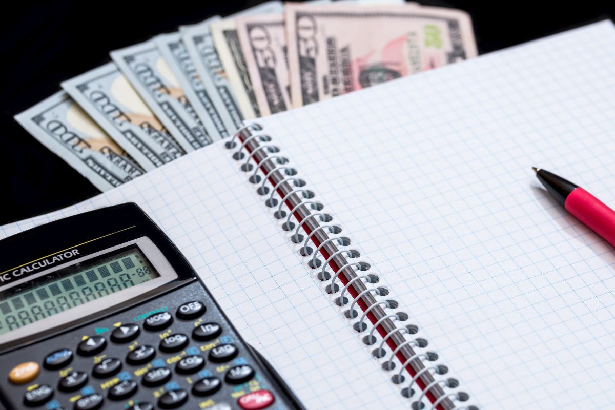 A photo of a calculator, money, and a notebook.