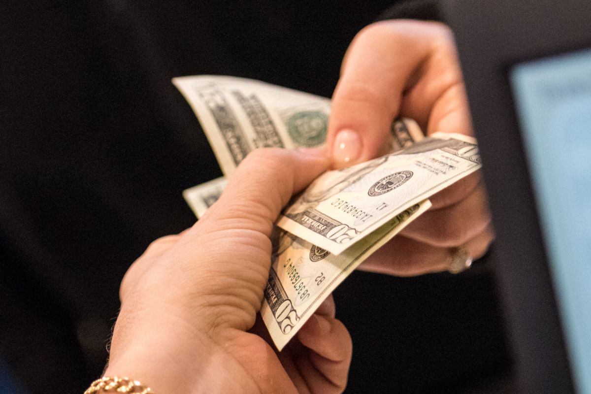 The photo shows a woman's hand paying in cash.